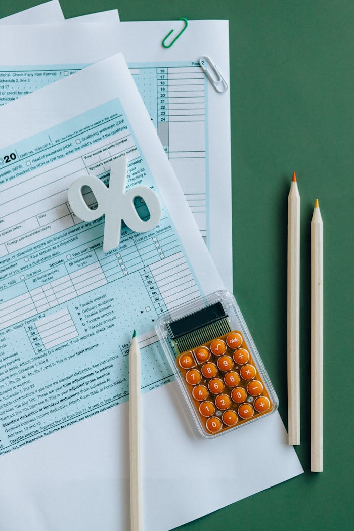 creative Flat lay of tax documents, calculator, and pencils on green surface.